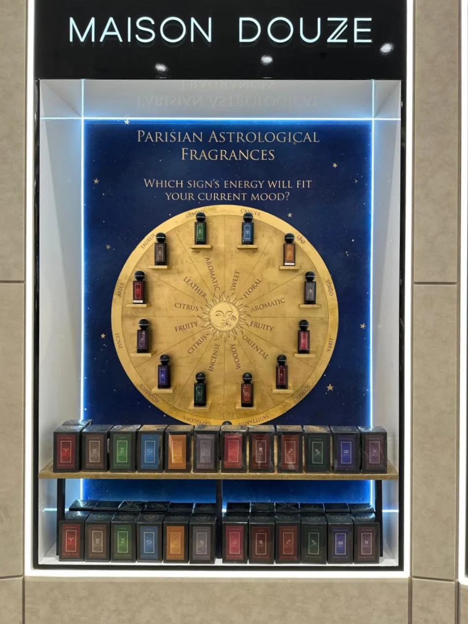 Maison Douze retail display with perfume bottles arranged around a circular astrological chart