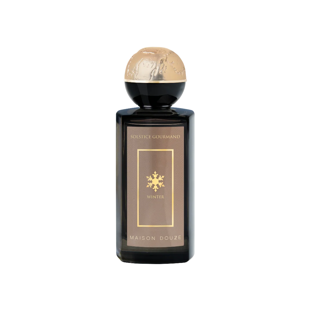 Maison Douze Solstice Gourmand perfume bottle in a peach-toned still life with gourmand ingredients