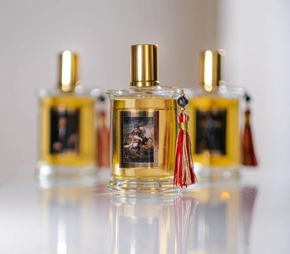 Three Parfums MDCI Painters and Perfumers bottles with framed historical artwork