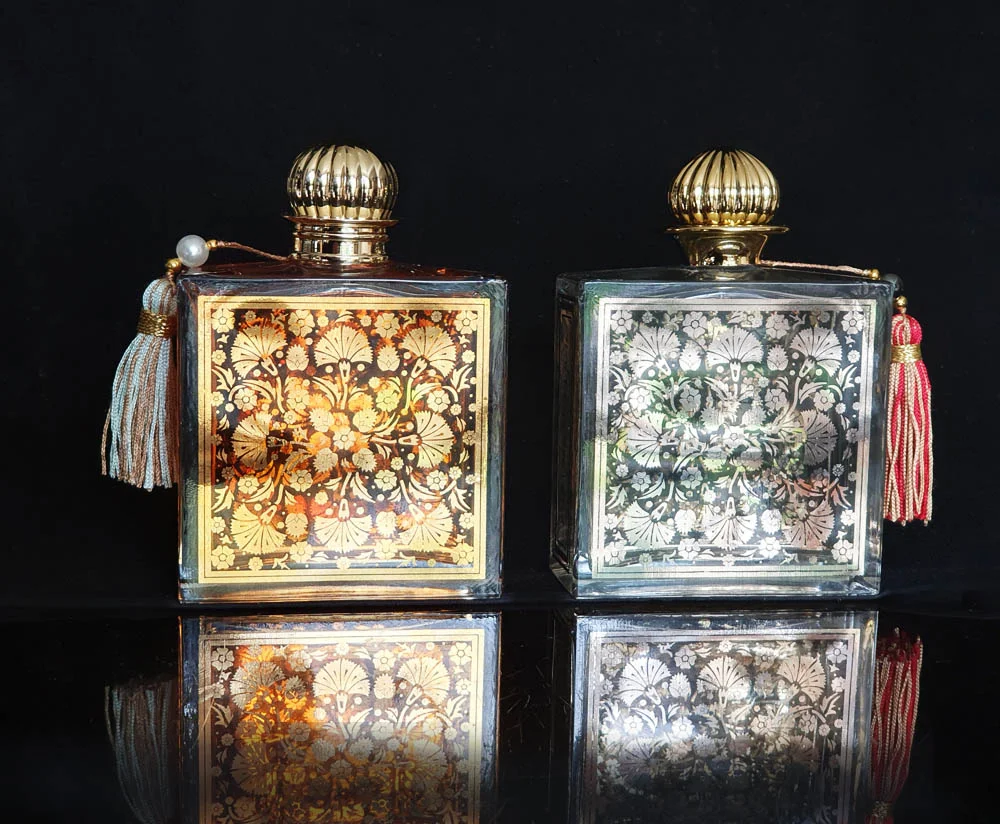 Two Parfums MDCI Silk Road perfume bottles with gold and platinum ornamental panels