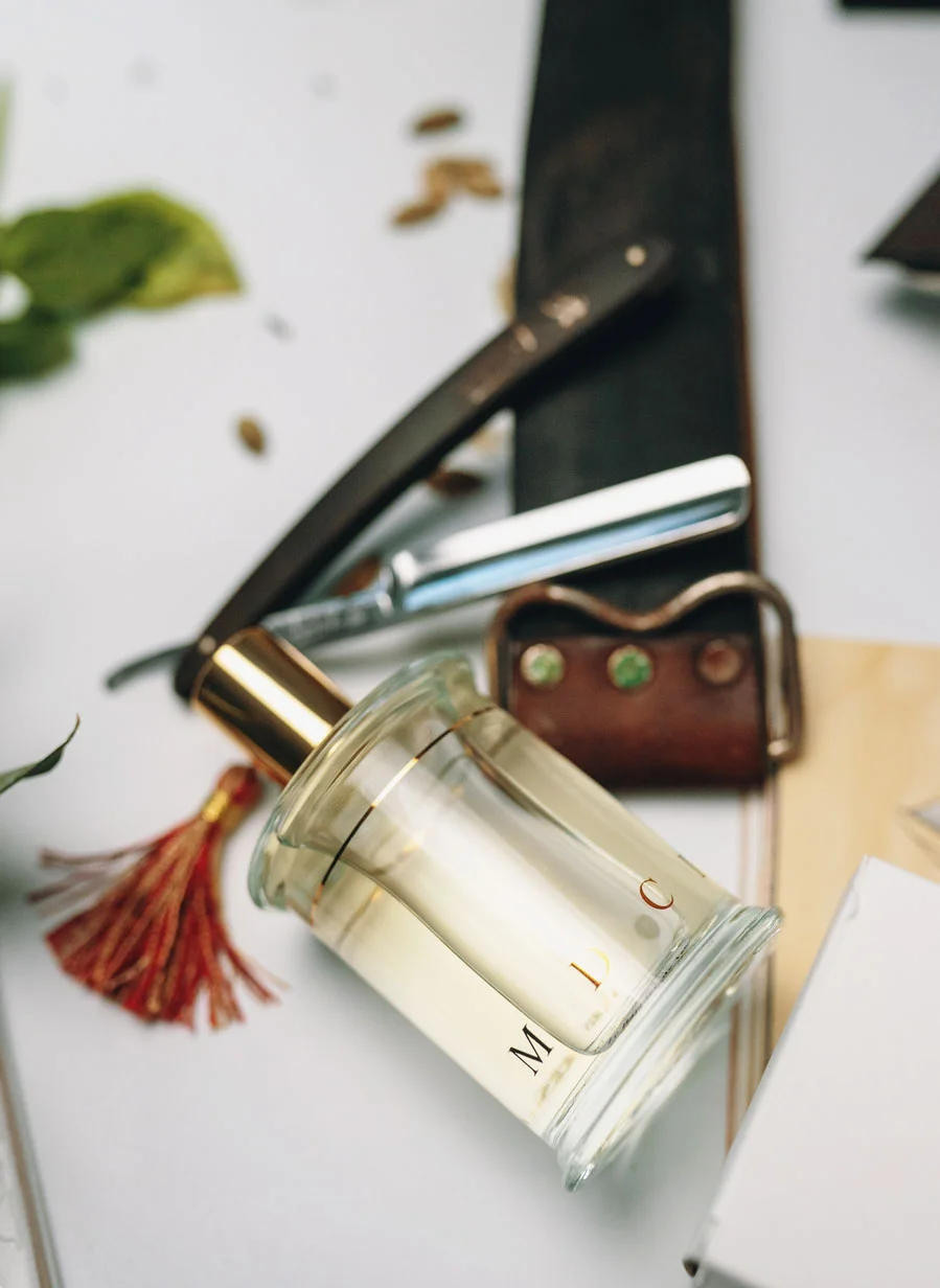 Parfums MDCI cylindrical perfume bottle shown with a red and gold tassel