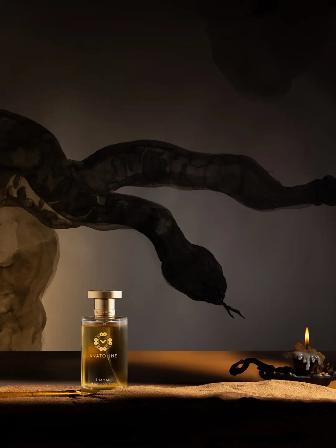 ANATOLINE Shaman perfume bottle in a dark campaign scene with candlelight and serpent-like forms
