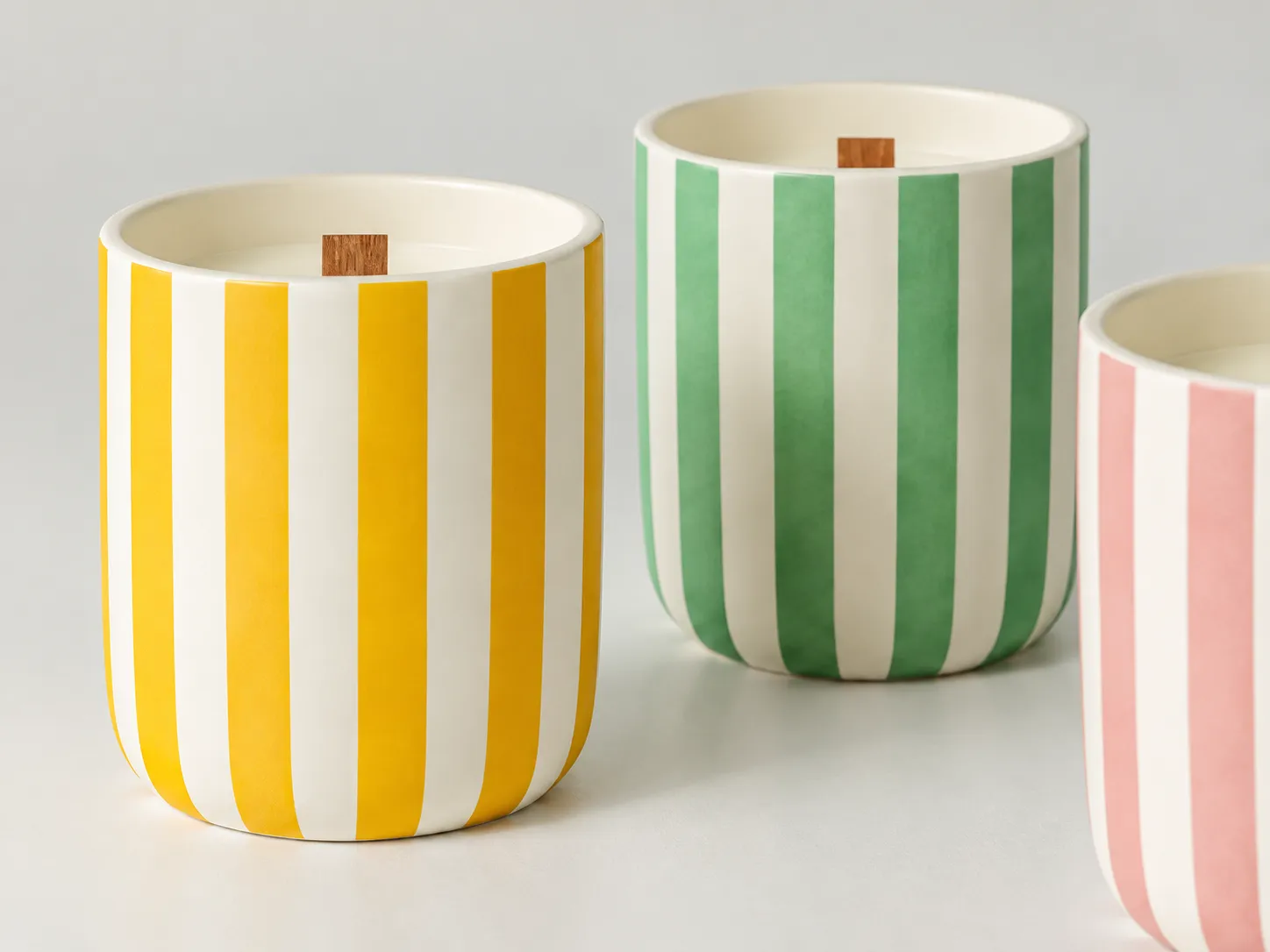 Close view of striped ceramic candle vessels showing yellow and green ceramic decal decoration